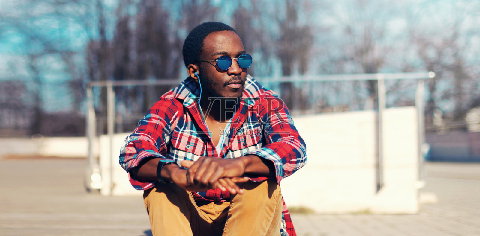 时尚的非洲男人的肖像听音乐与耳机在城市照片摄影图片