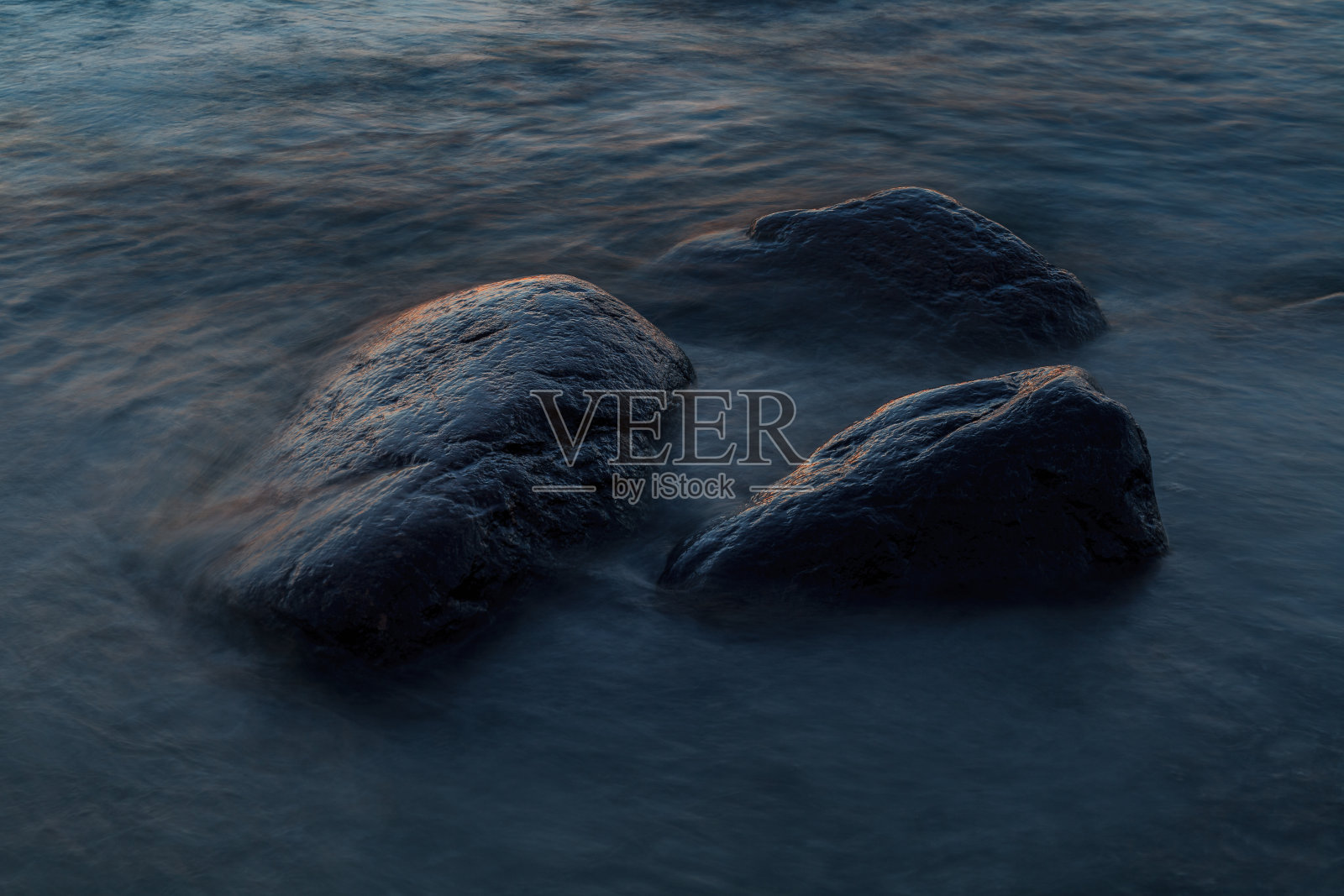 美丽的红色日落带在深蓝色的大海和巨石上。波罗的海,爱沙尼亚。照片摄影图片