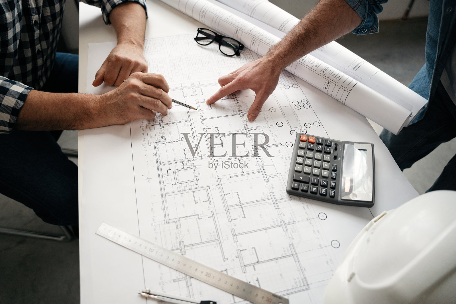 建筑师和工程师在桌子上讨论蓝图-手部特写和项目打印。照片摄影图片