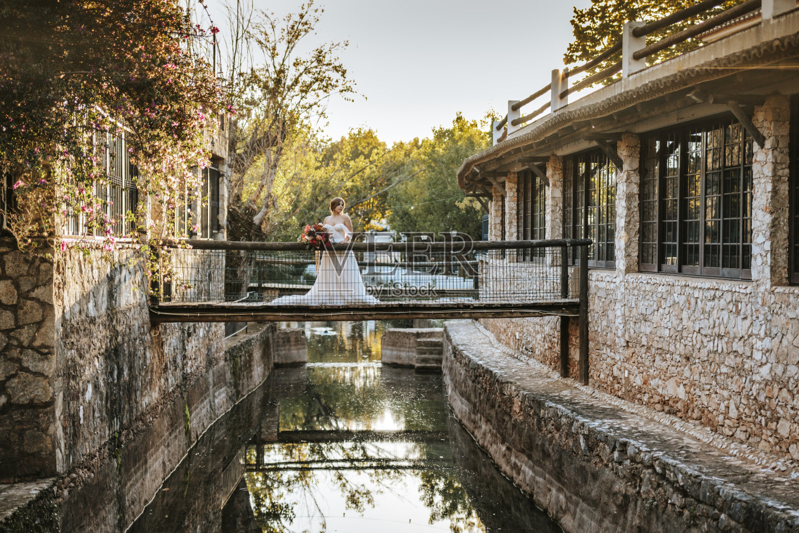 日落时分,美丽的新娘站在木桥上照片摄影图片
