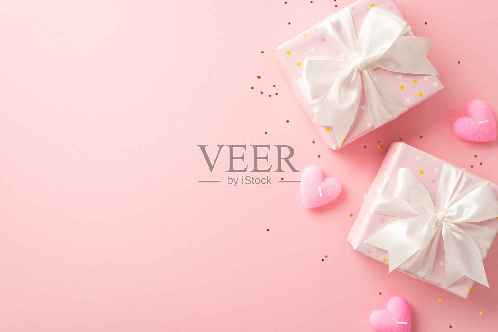 情人节的概念。顶部视图照片的礼盒与白色丝带蝴蝶结心形蜡烛和金色亮片在孤立的浅粉色背景与复制空间照片摄影图片