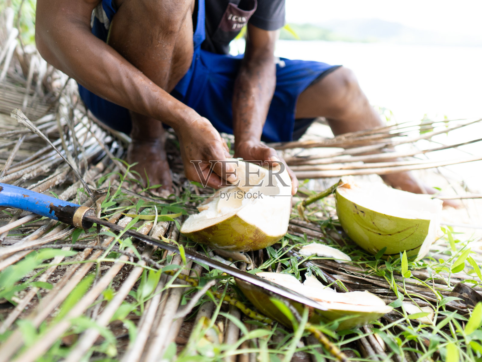 一个年轻的菲律宾渔民在菲律宾的一个热带岛屿上吃椰子的手。真正的人,传统的工作照片摄影图片