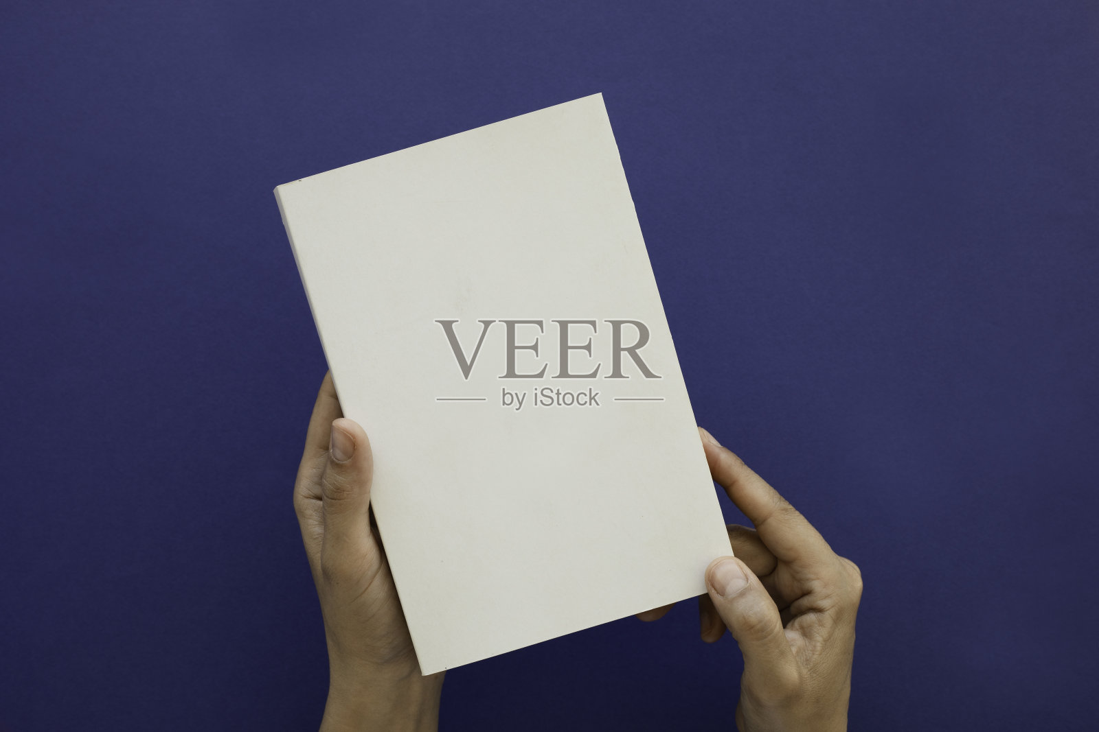 裁剪的手男子拿空白的书对蓝色的背景照片摄影图片