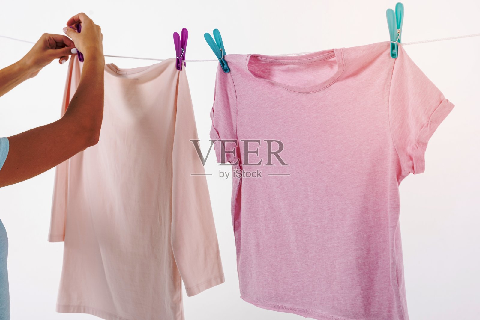 女人用衣服别针固定t恤晾衣绳照片摄影图片