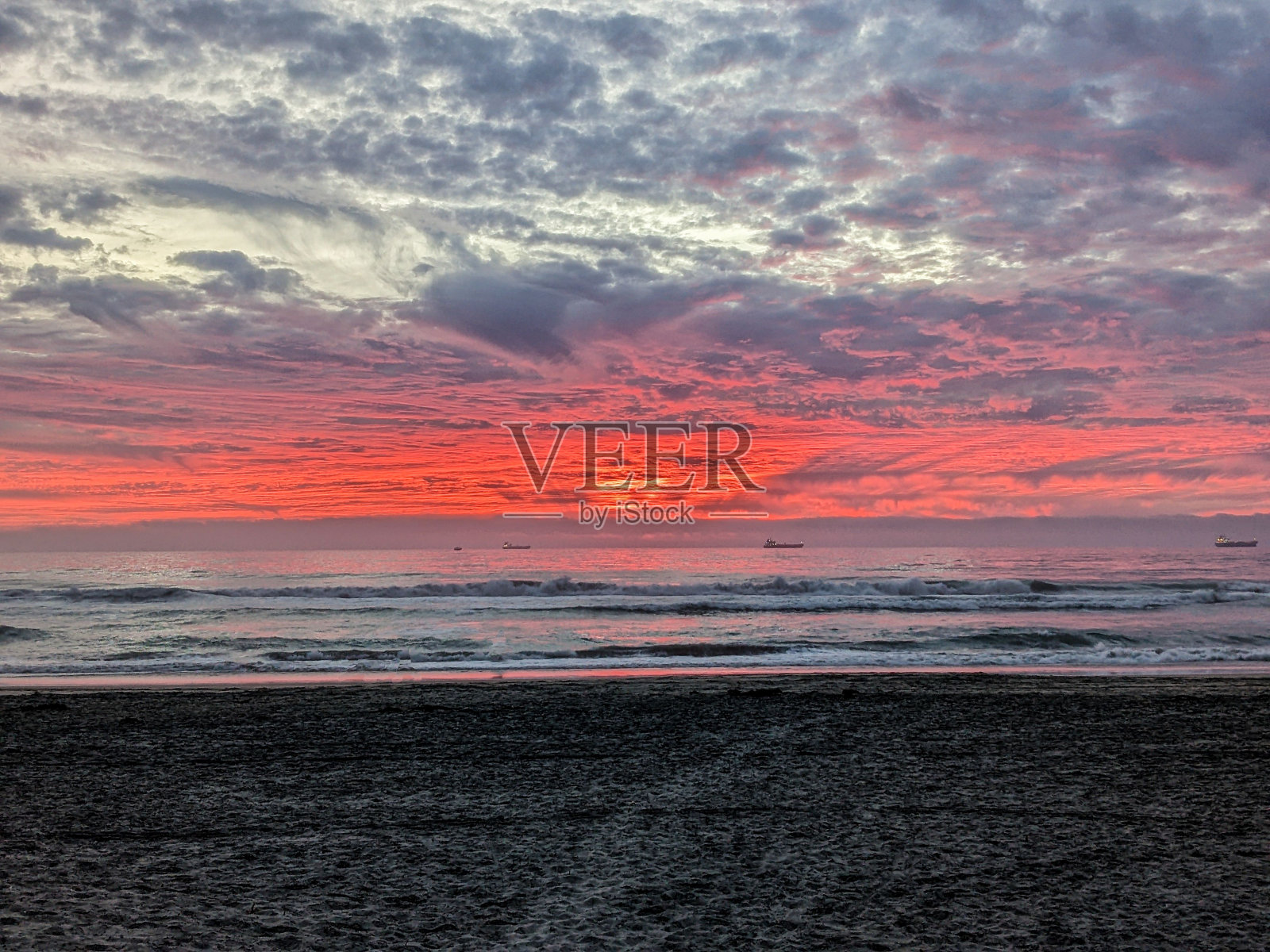 宁静的大海和远处粉红色天空下的船的海岸风景照片摄影图片