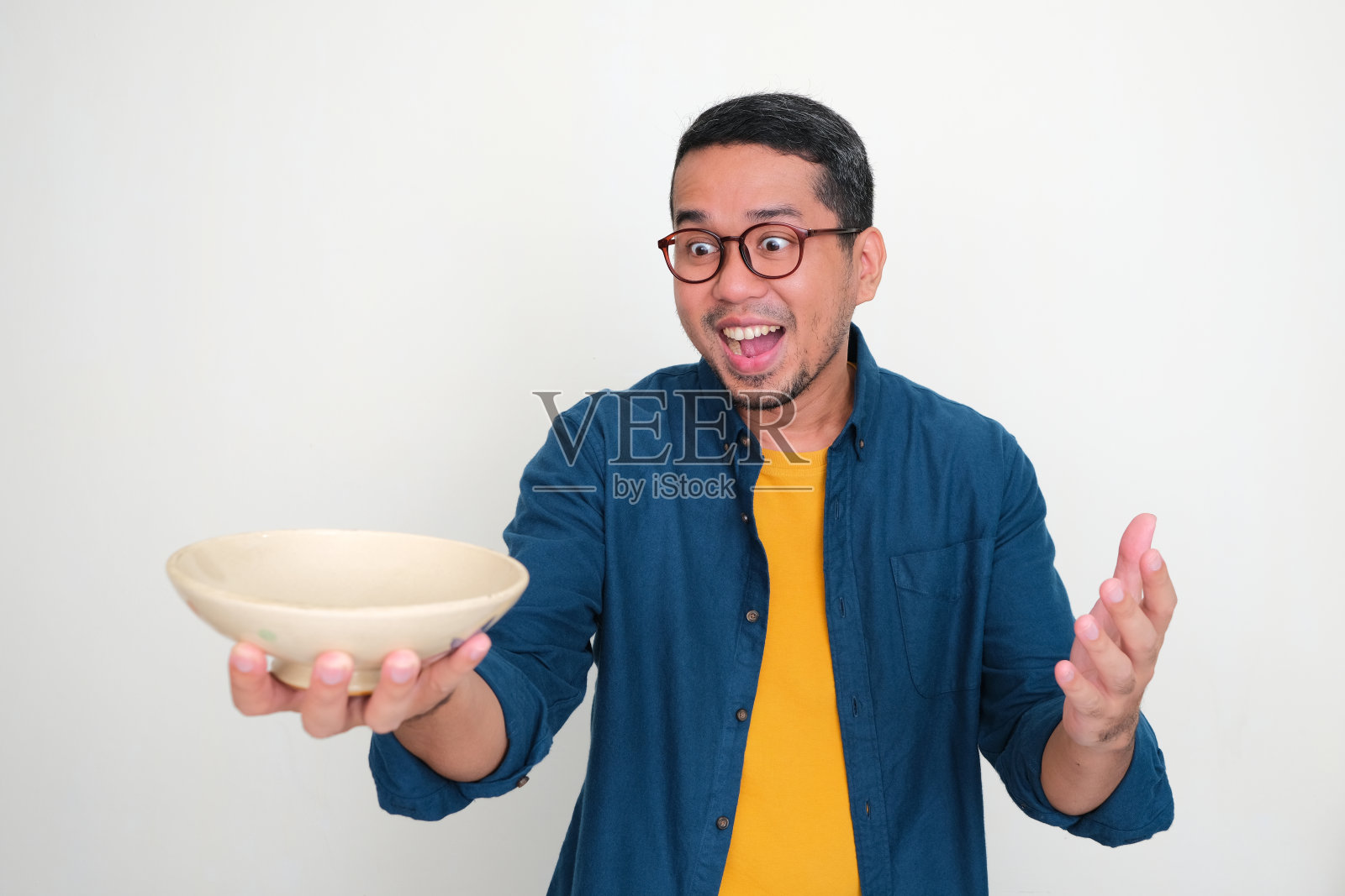 成年亚洲男子看着空碗,他拿着兴奋的表情照片摄影图片