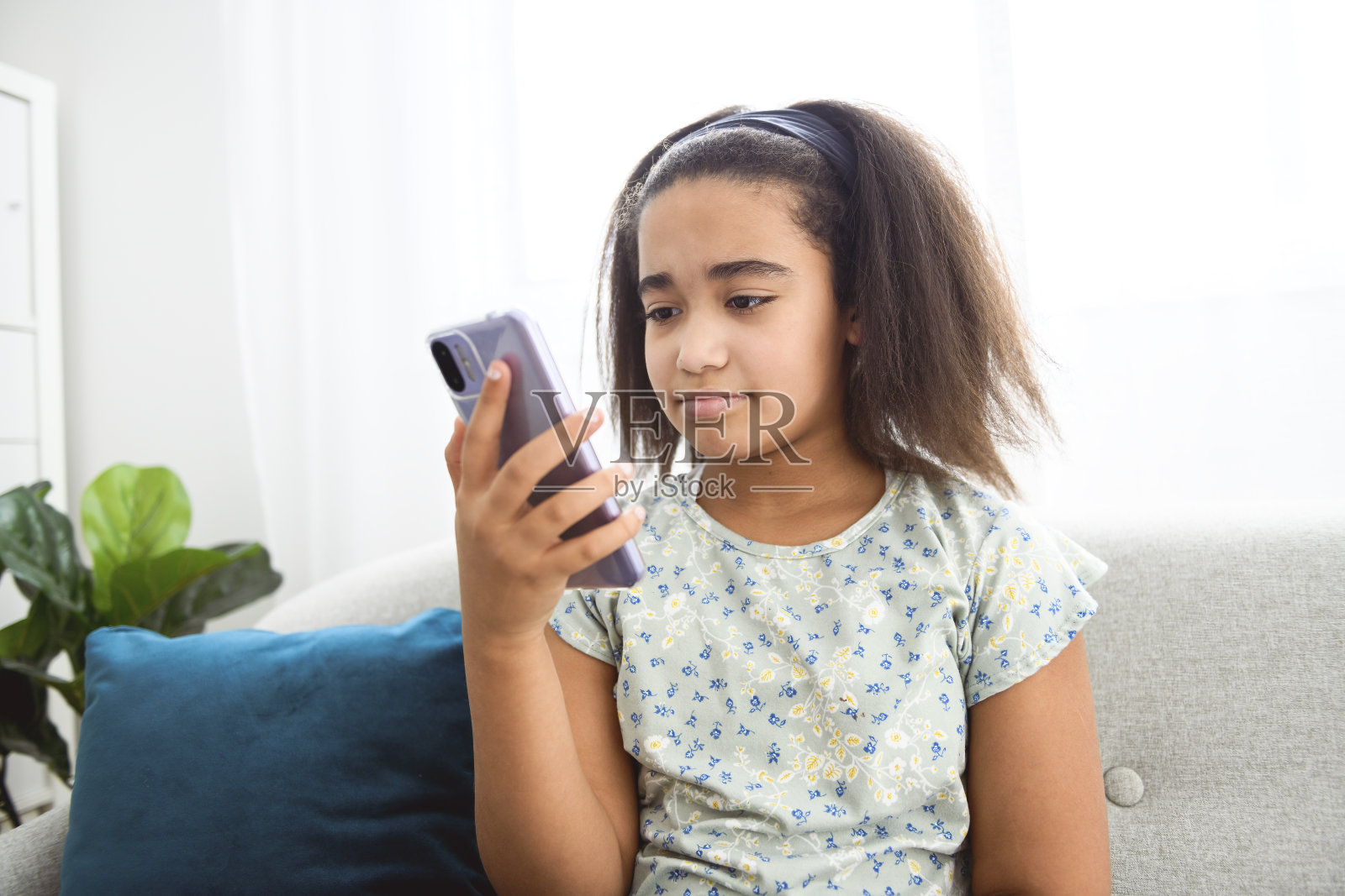 美国少女坐在家里的沙发上用手机照片摄影图片