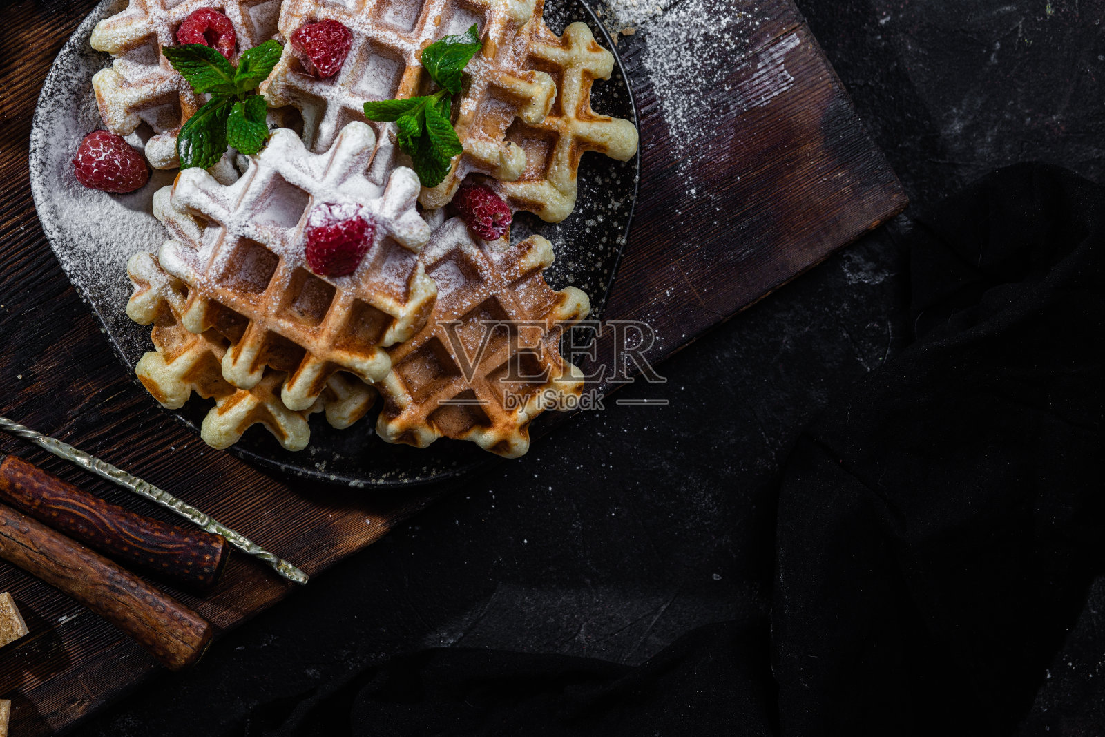 深色盘子里的比利时华夫饼,覆盆子和薄荷照片摄影图片