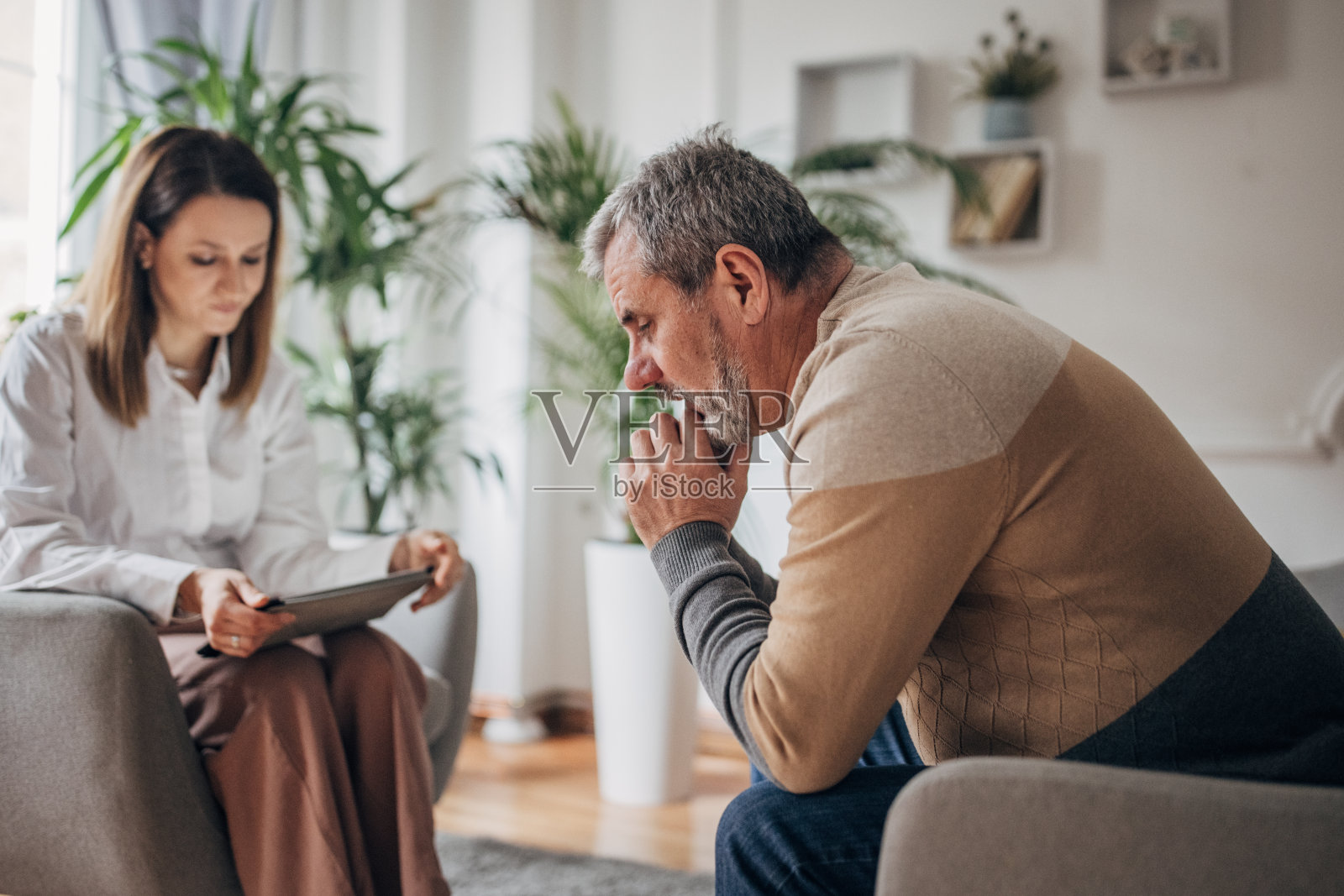 心理治疗,年轻的女医生和一个年长的男人谈话照片摄影图片