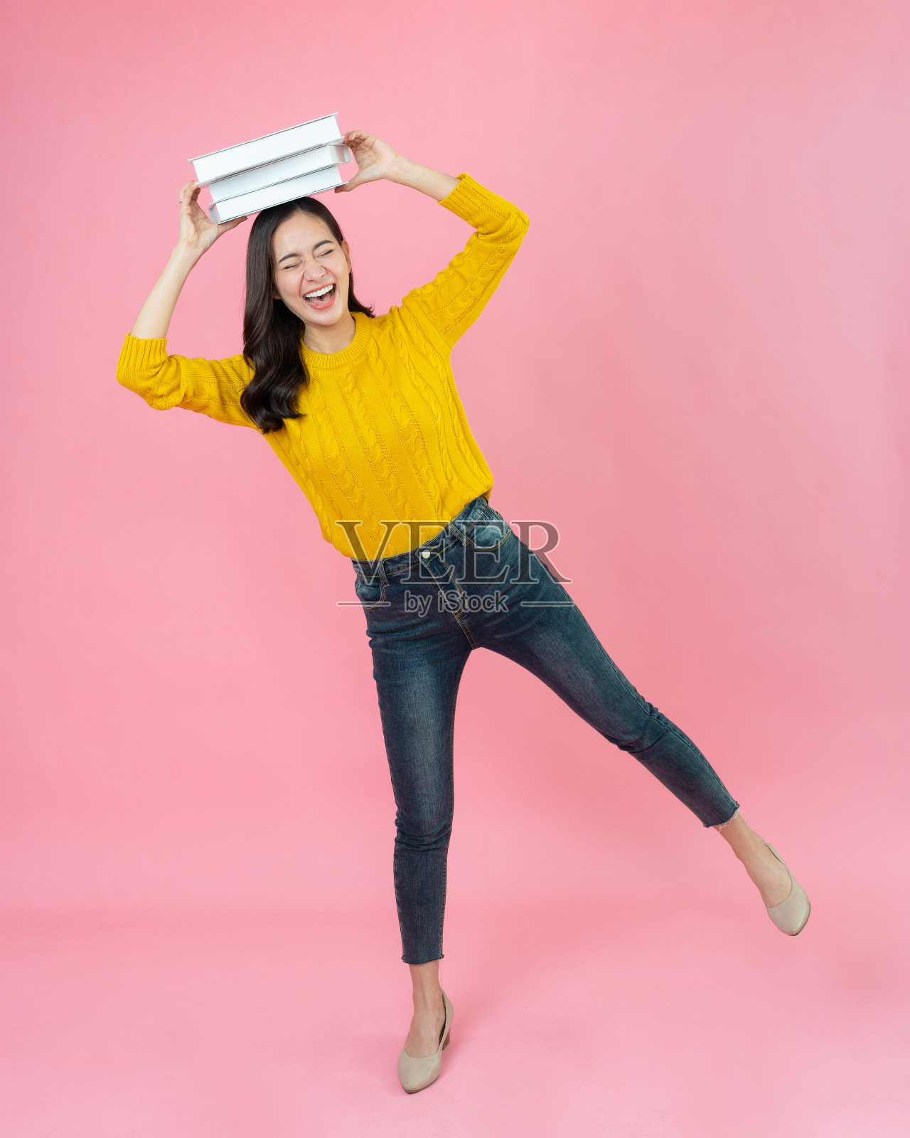 年轻的亚洲女性拿着书,在粉红色的背景下微笑。快乐的女学生。教育的概念照片摄影图片