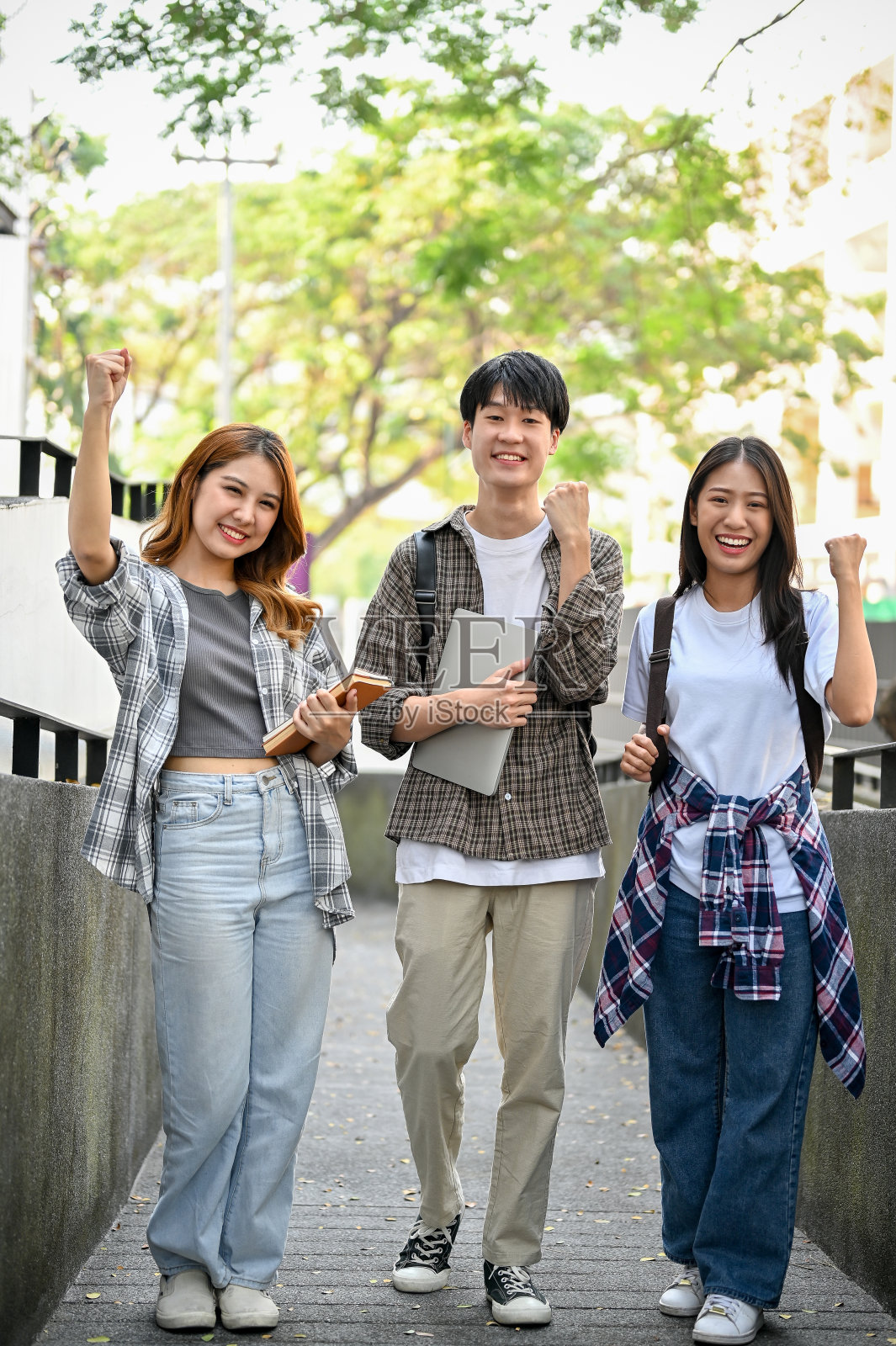 一群欢快的亚洲大学生挥舞拳头,庆祝胜利,享受大学生活。照片摄影图片