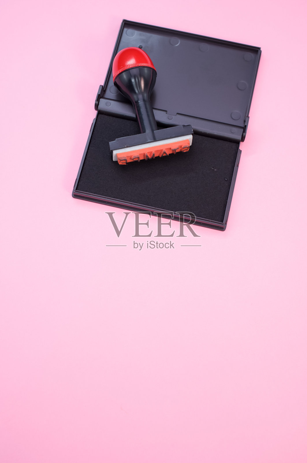 黑色墨垫与橡皮图章隔离在粉红色背景上照片摄影图片