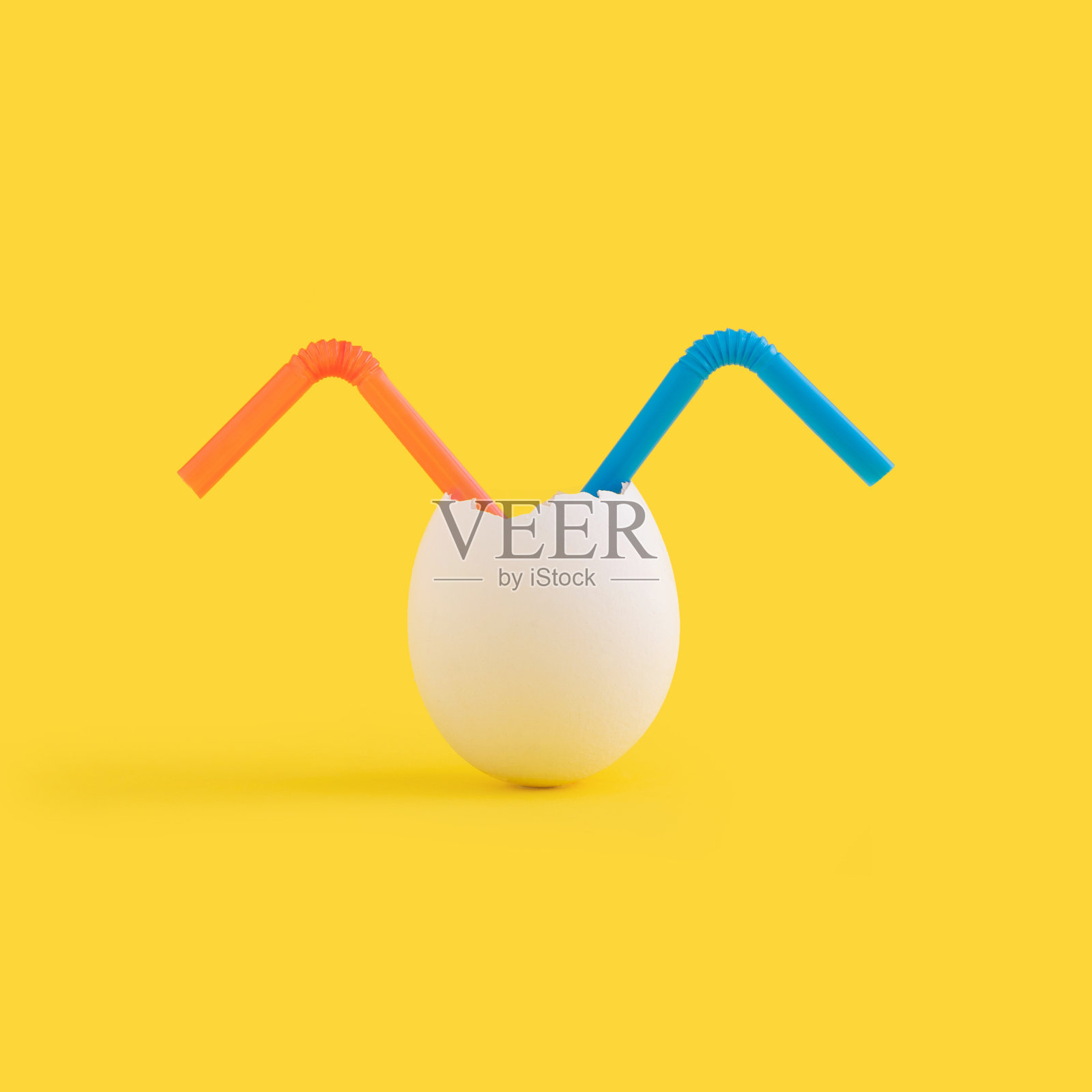 黄色背景下蛋壳里的两根塑料吸管特写照片摄影图片