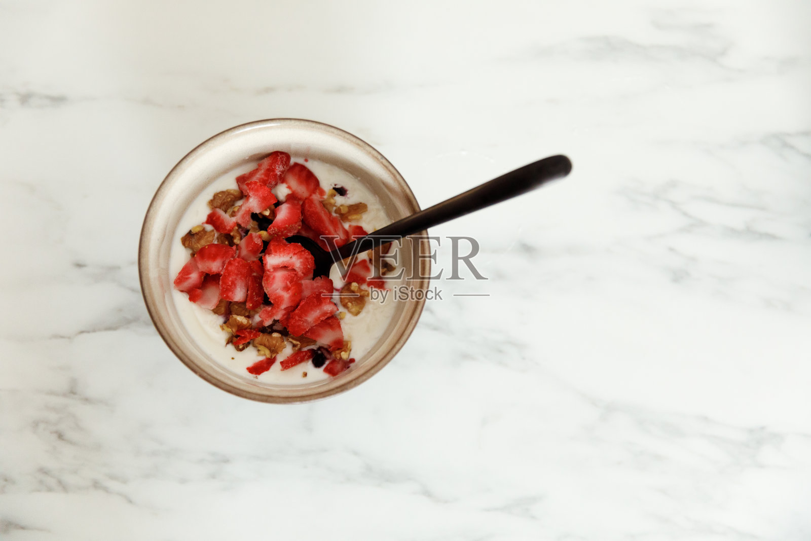 一碗加香蕉、杏仁的健康酸奶,桌上放一个勺子照片摄影图片