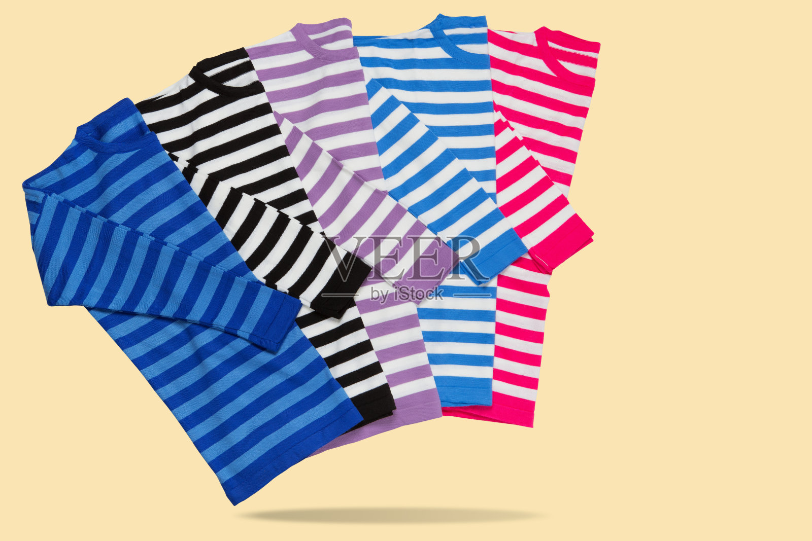 四件不同颜色的条纹毛衣,好像在走路,互相拥抱,概念,在黄色背景上照片摄影图片