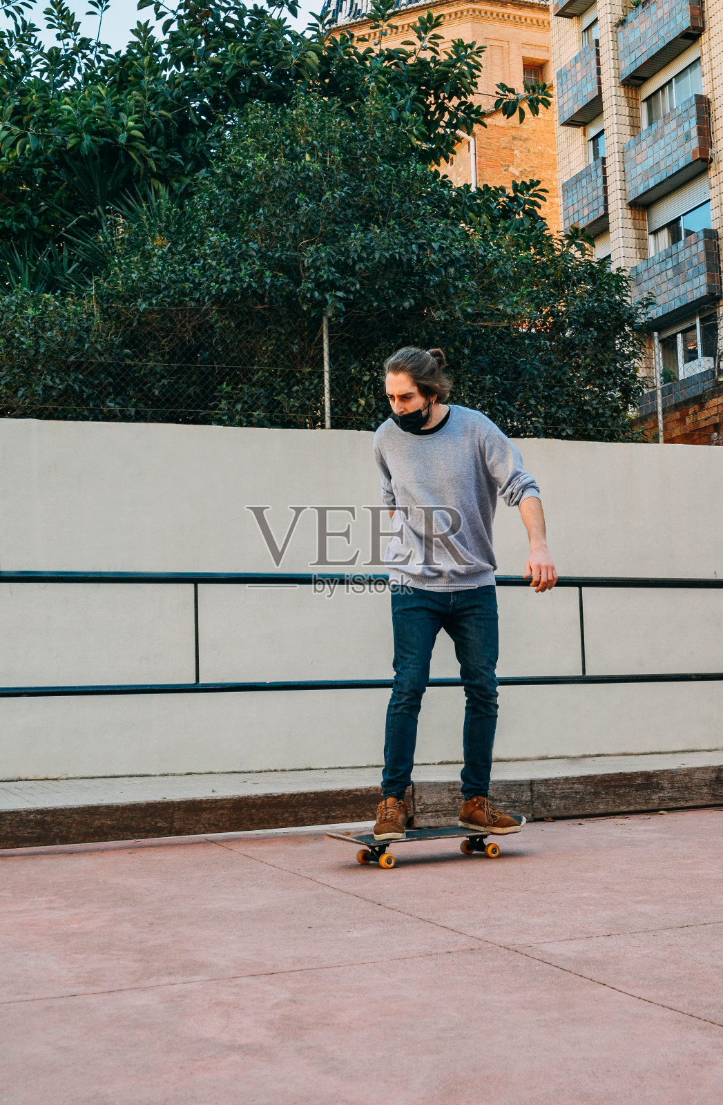 垂直拍摄的男性滑手与黑色面具滑板在公园轨道照片摄影图片