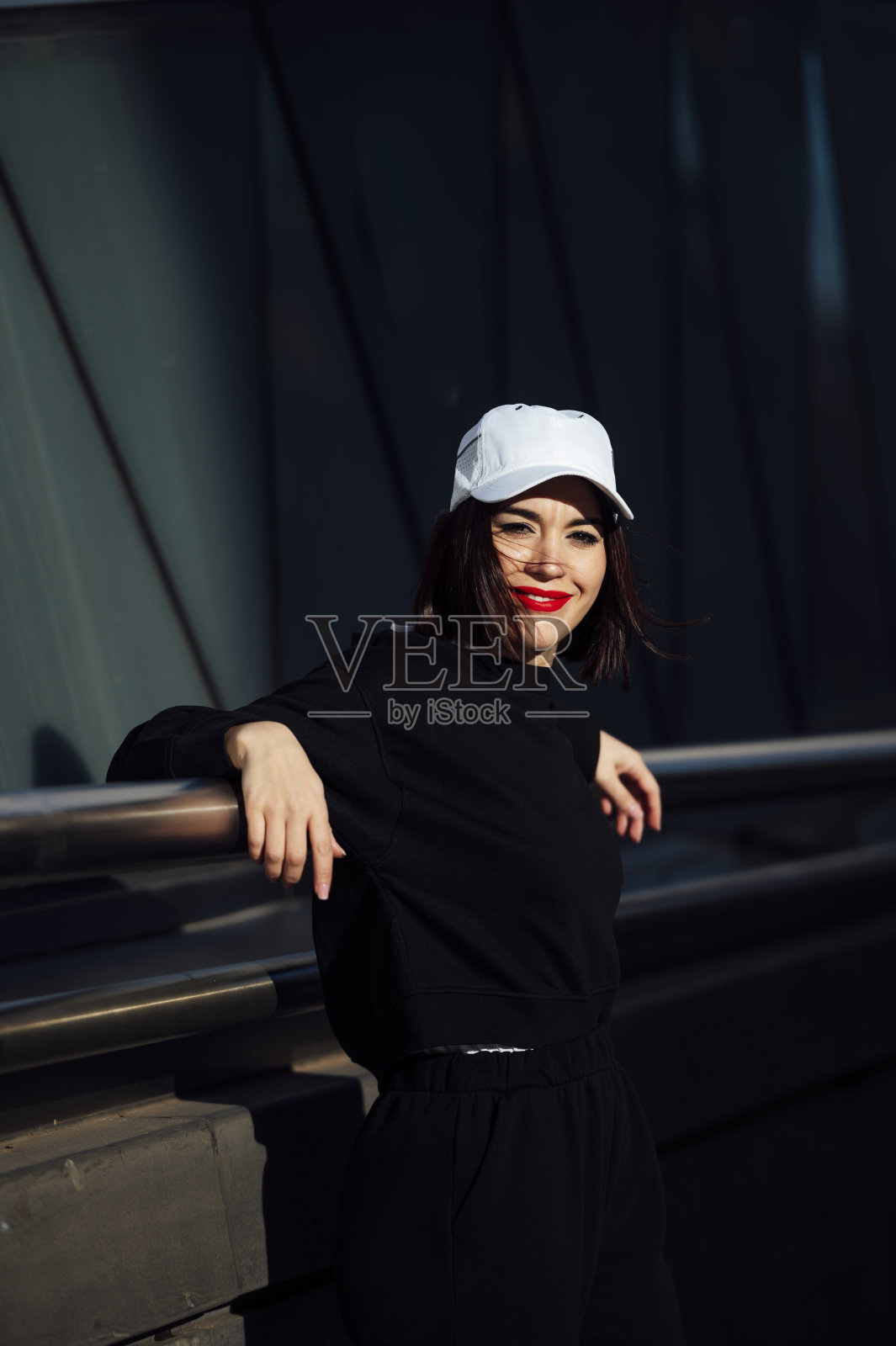 一个涂着红色口红的白人妇女靠在栏杆上的垂直镜头照片摄影图片