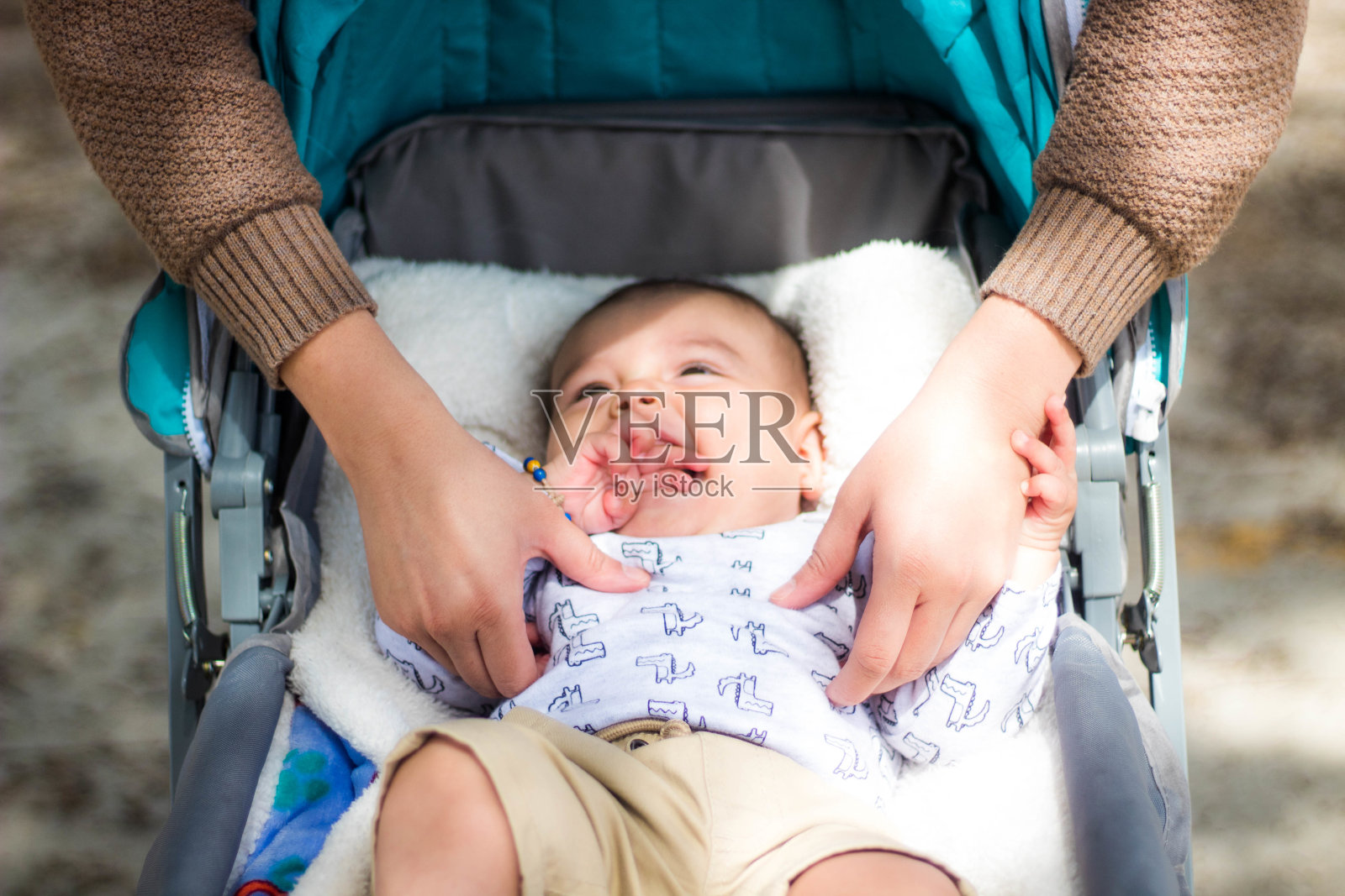 在公园里,一位母亲在婴儿车里和一个可爱的快乐的孩子玩耍照片摄影图片