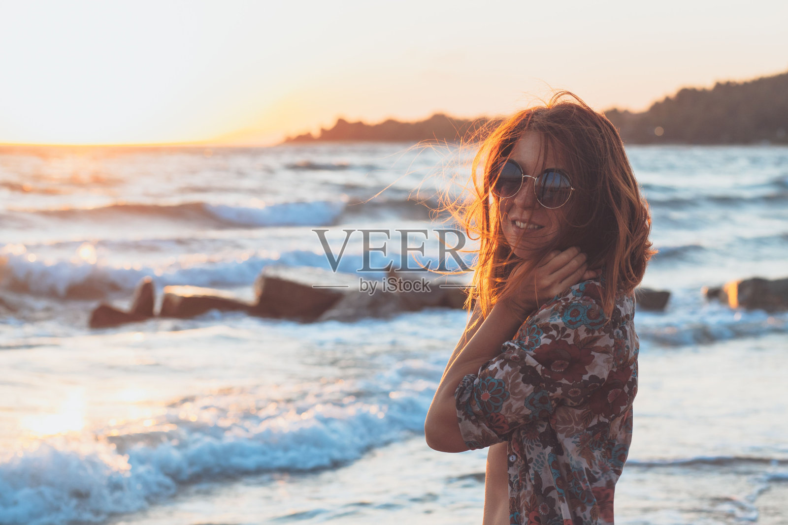 美丽的白人女孩在日落时在海滩上摆姿势,享受夏天照片摄影图片