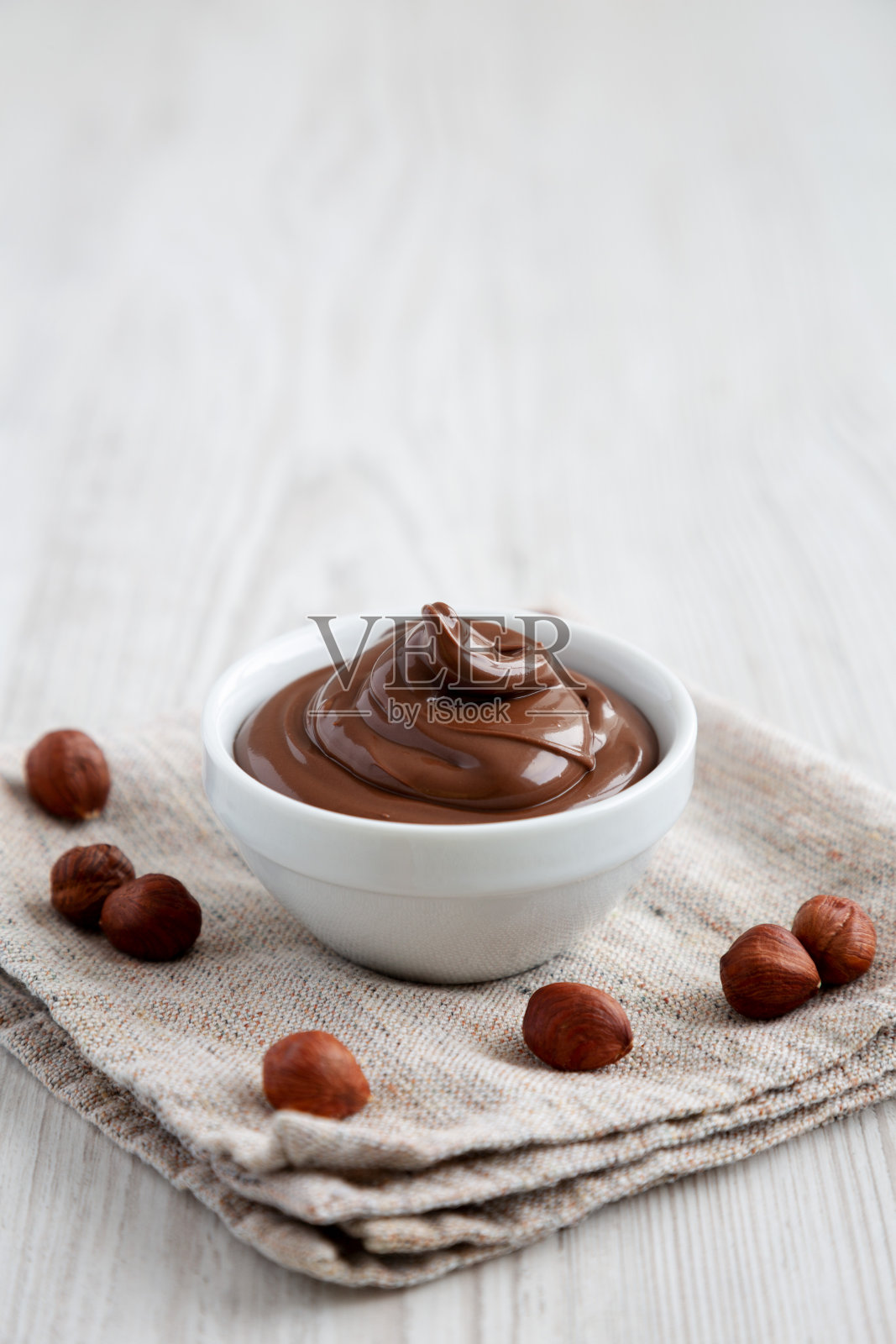 自制的榛子巧克力摊在碗上的白色木制背景,侧面视图。副本的空间。照片摄影图片