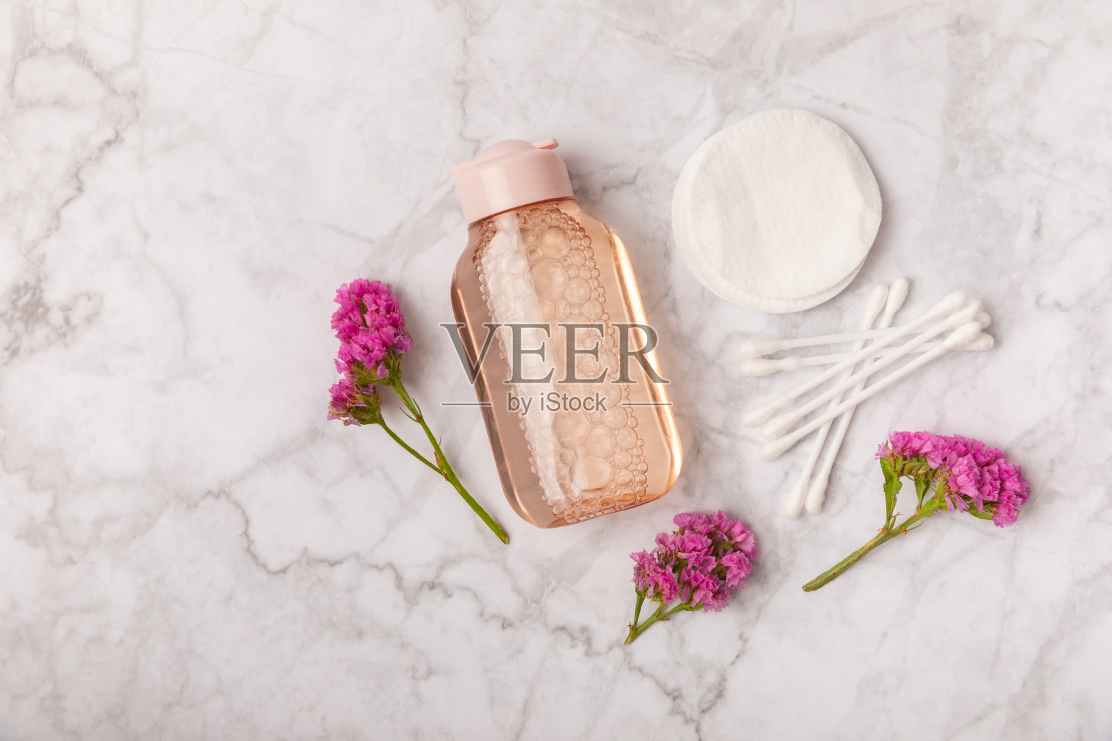 胶束清洁水和棉垫在大理石背景上。洗面奶或卸妆化妆品瓶在浴室。护肤理念。清洁面部彩妆及皮肤皮脂。照片摄影图片