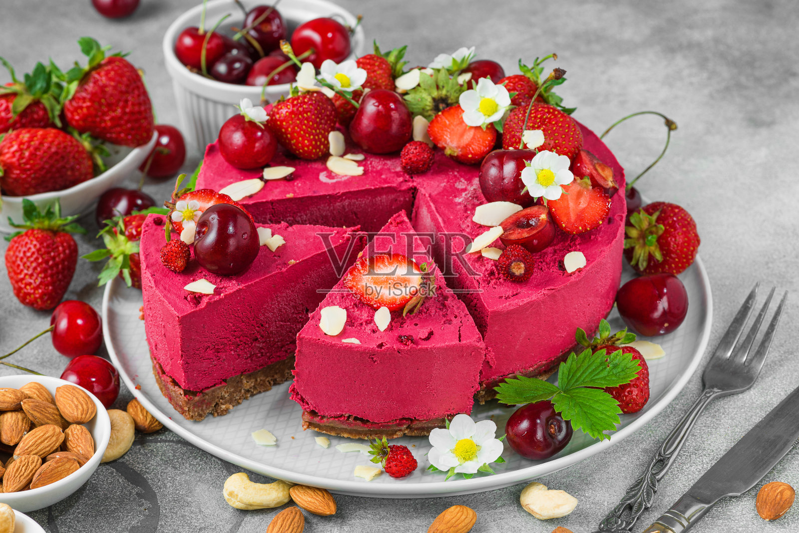 素食甜点。切片生浆果腰果蛋糕,新鲜草莓和樱桃在盘子里照片摄影图片