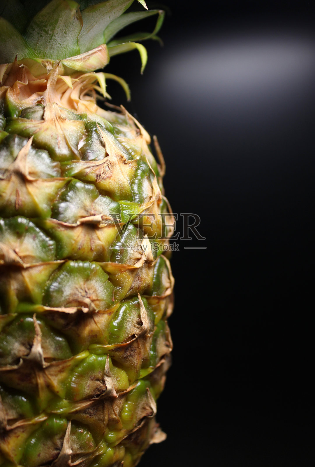 半个完整菠萝,部分绿叶在黑色背景上的竖版照片照片摄影图片
