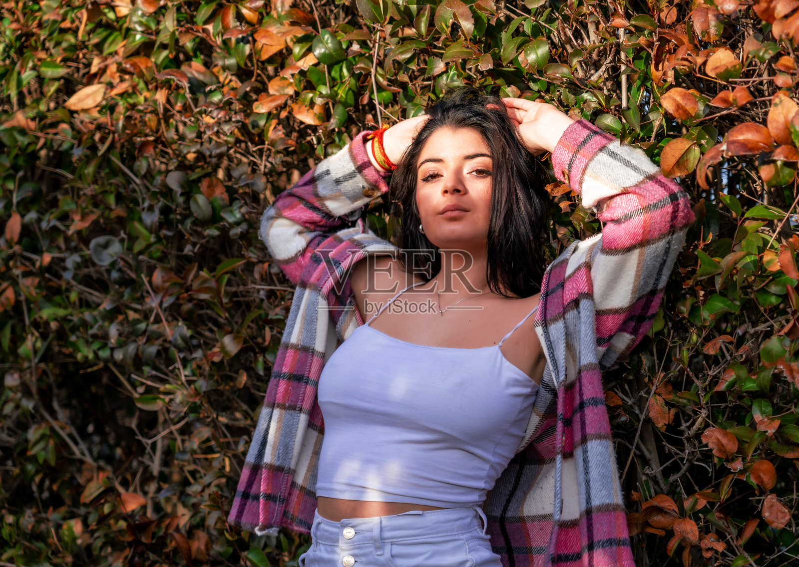 白人年轻女子在白色裙子附近摆姿势的叶子照片摄影图片