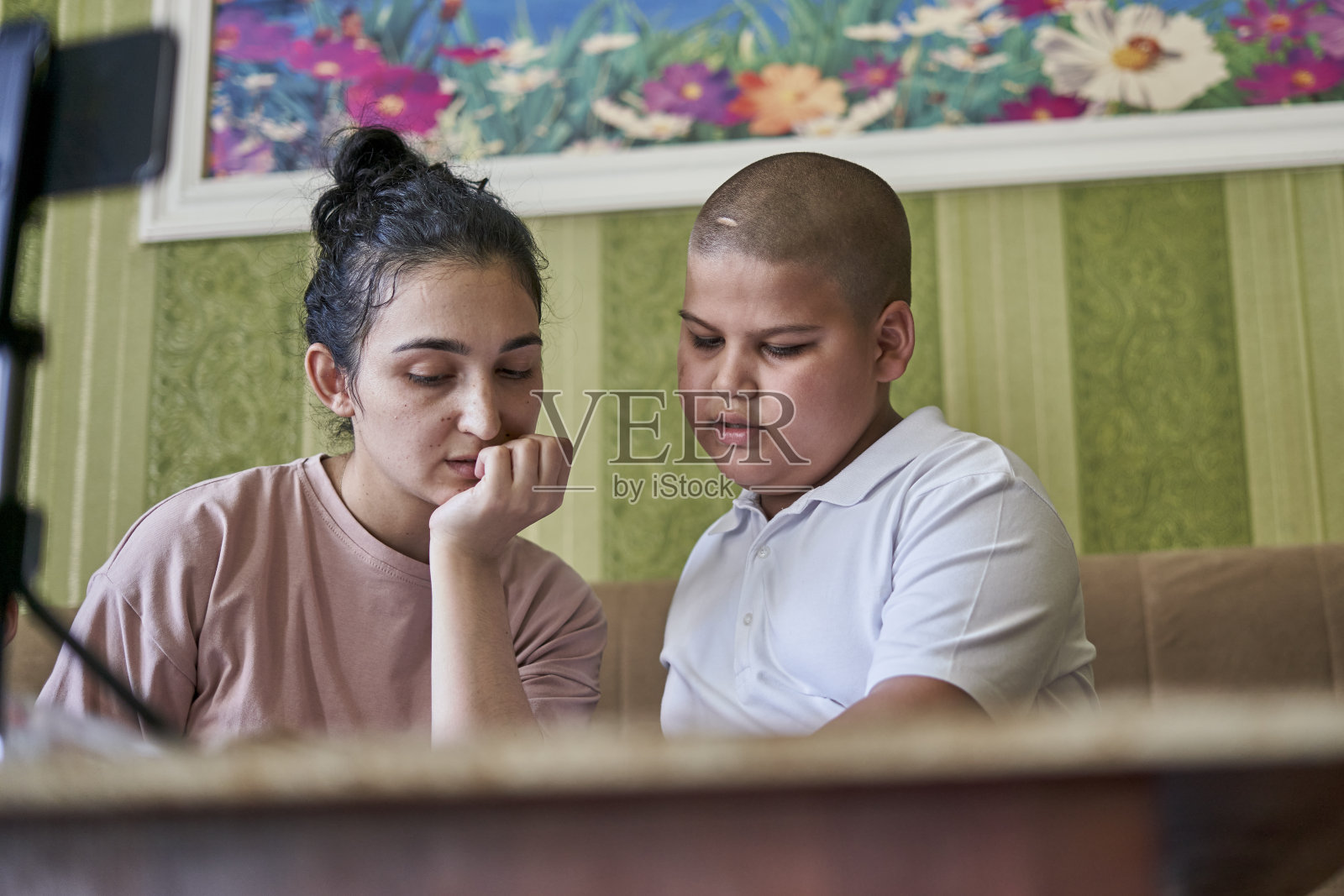 一名年轻的女教师在网上课堂上给一名年轻的学生讲解课文照片摄影图片