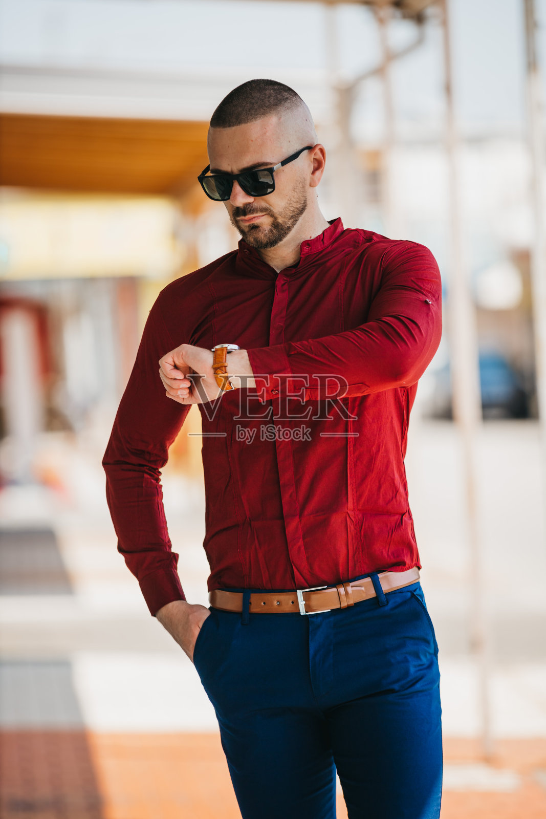 帅气的白人男子穿着优雅的红色衬衫,戴着太阳镜在户外摆姿势照片摄影图片