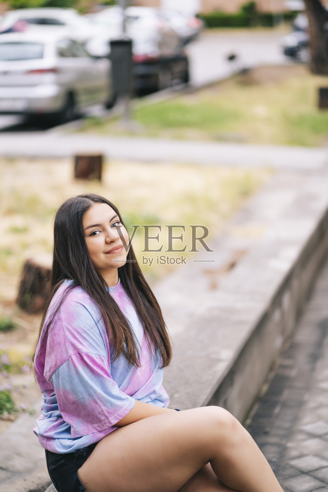 一个年轻胖乎乎的白人女士穿着t恤和短裤坐在户外的垂直镜头照片摄影图片