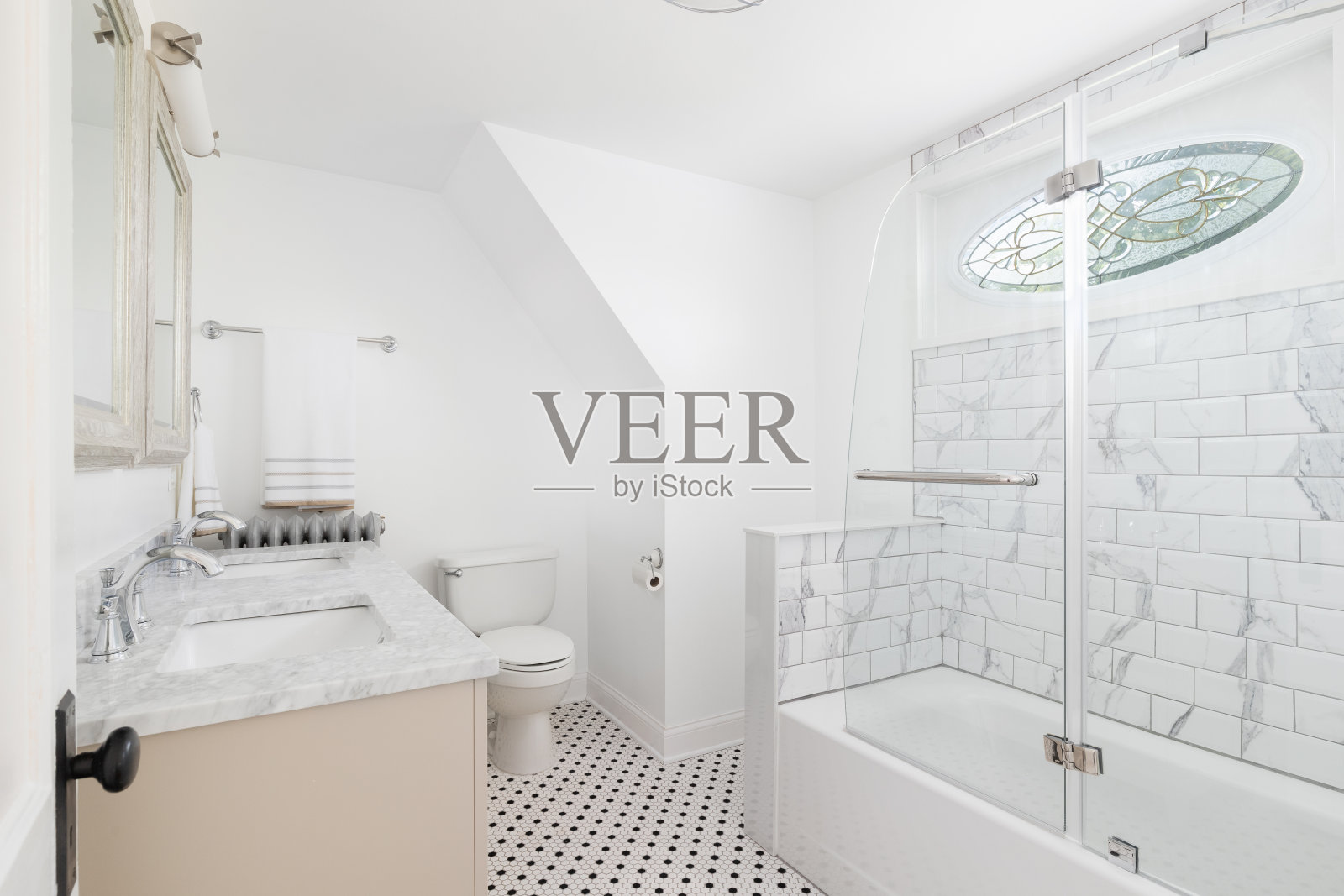 一间带有奶油色橱柜和地铁瓷砖淋浴的浴室。照片摄影图片