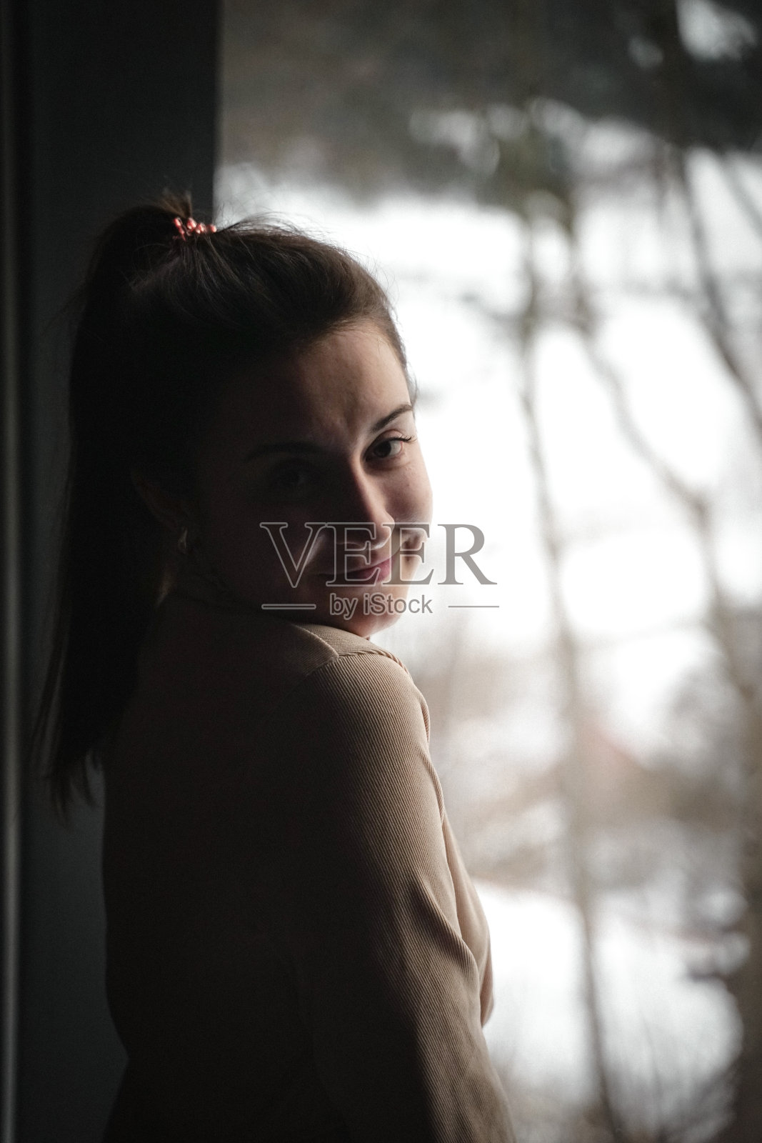 一个白人妇女站在窗边的垂直镜头照片摄影图片