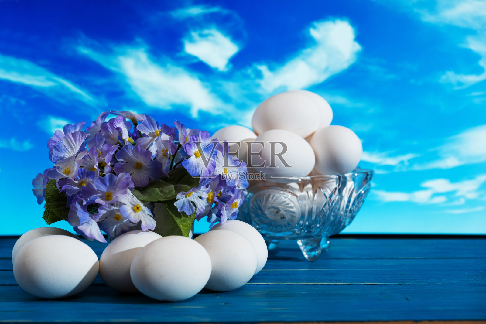 鸡蛋和花盆里的鲜花映衬着窗外的蓝天。复活节。照片摄影图片