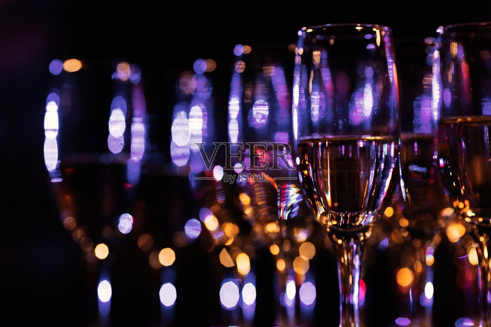 在一间昏暗的房间里,有几排模糊的香槟酒杯照片摄影图片
