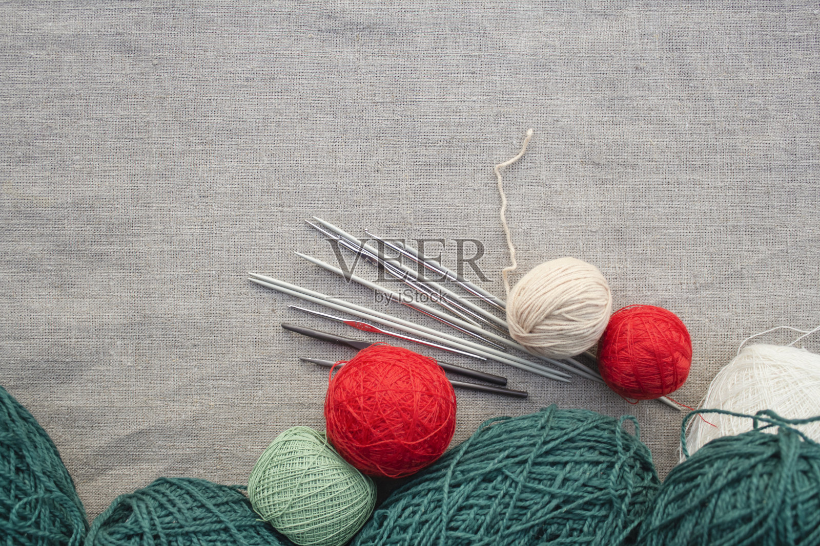 桌布上放着各种颜色的毛线、针织针和钩子。照片摄影图片