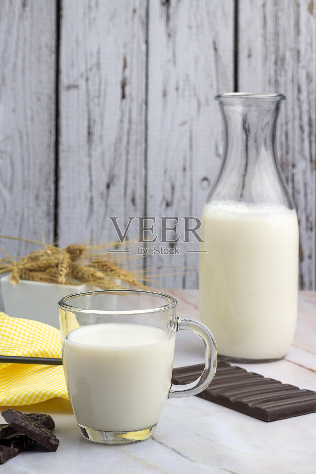 垂直拍摄的白色桌子上有一个玻璃杯和一瓶牛奶,周围有巧克力棒照片摄影图片