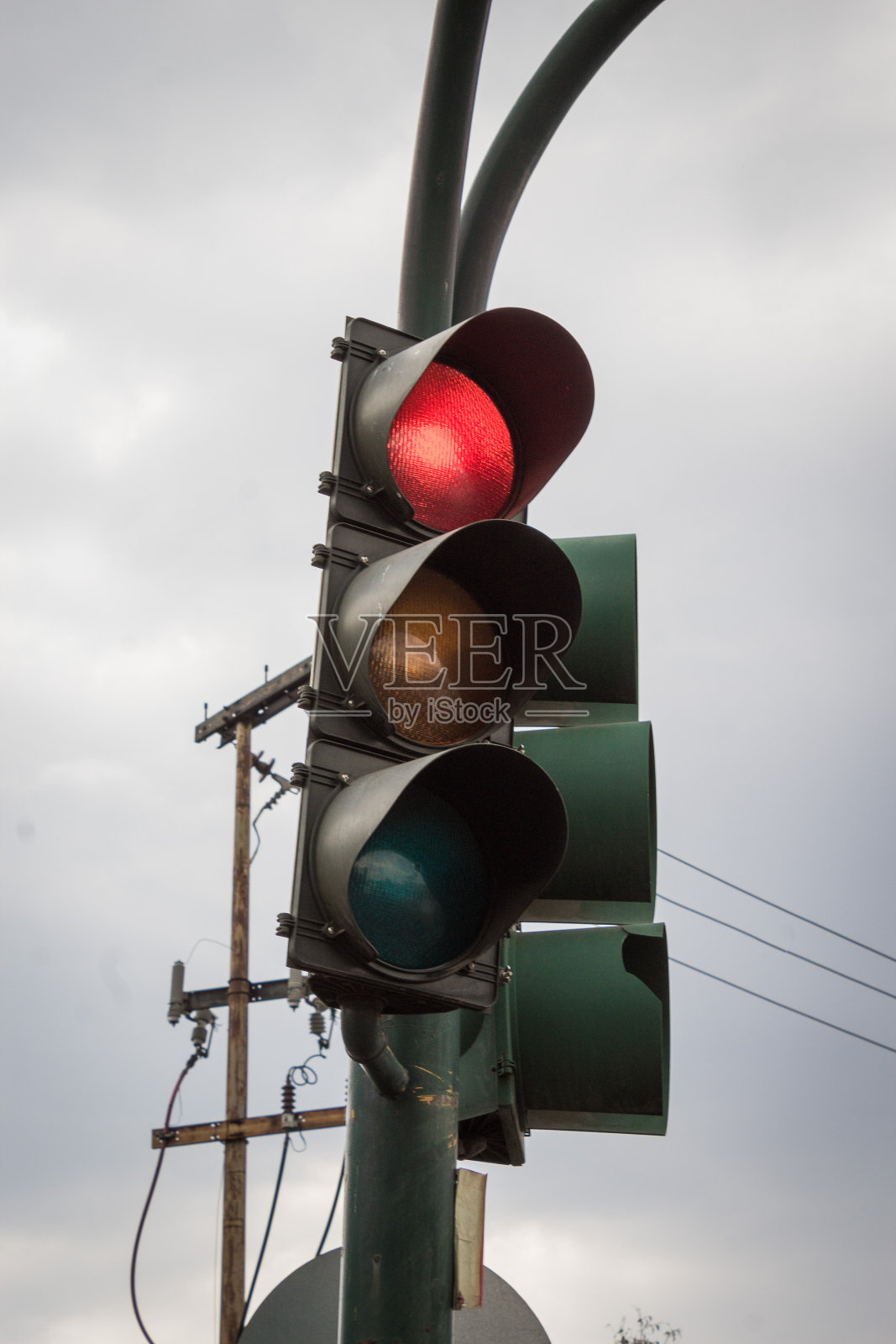 低角度拍摄的红绿灯在多云的天空下呈现出红色照片摄影图片