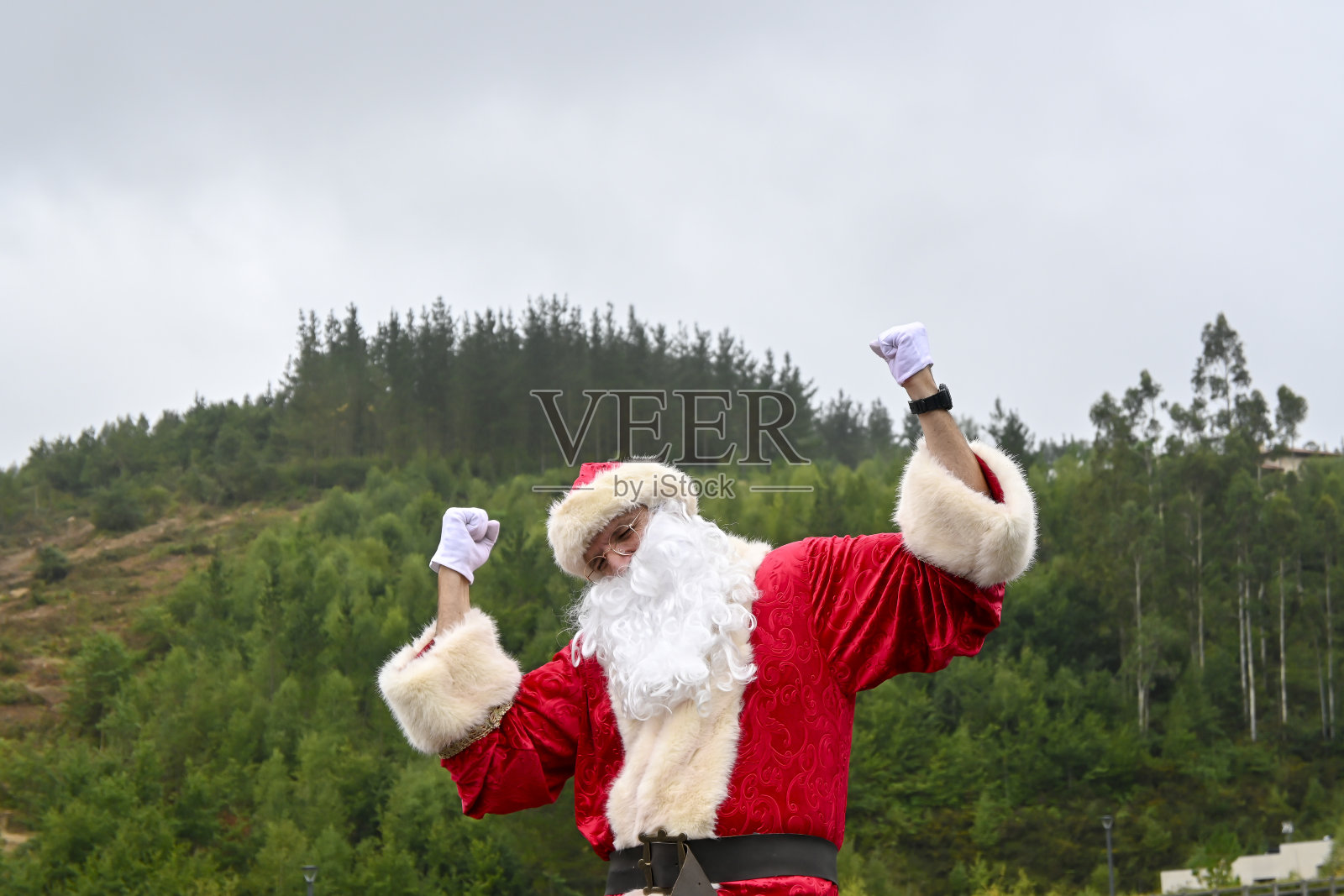 穿着圣诞老人服装的年轻男子在户外摆着滑稽的姿势照片摄影图片