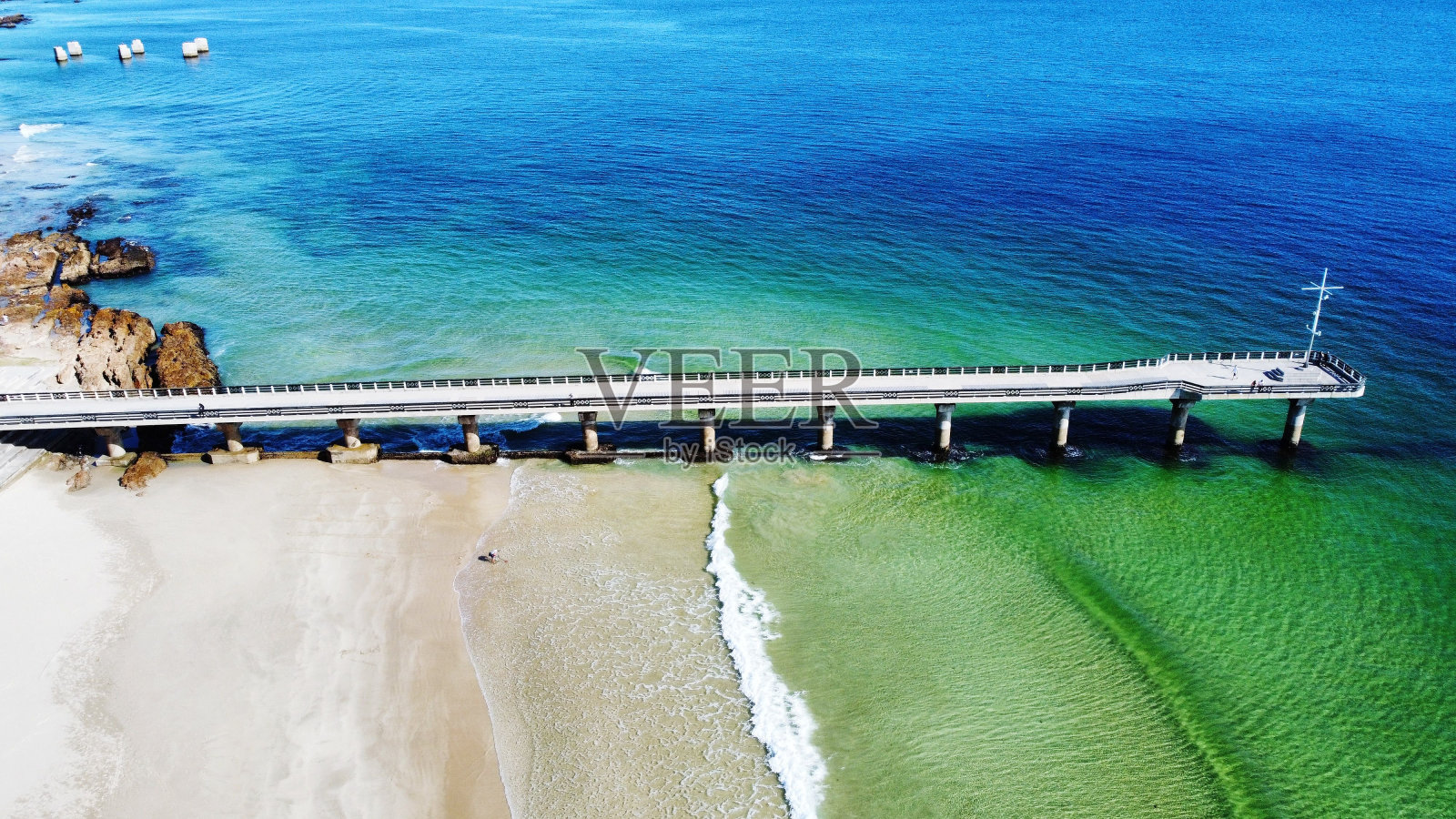 空中拍摄的泡沫海浪冲击着岸边的一个大码头照片摄影图片