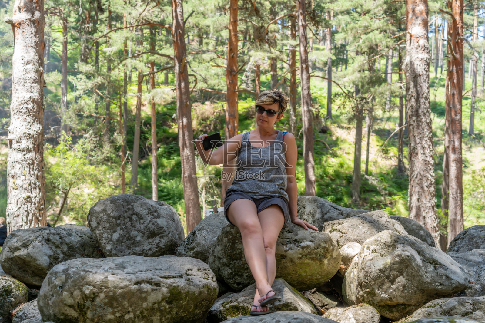 金发短发的白人女子坐在岩石上自拍照片摄影图片
