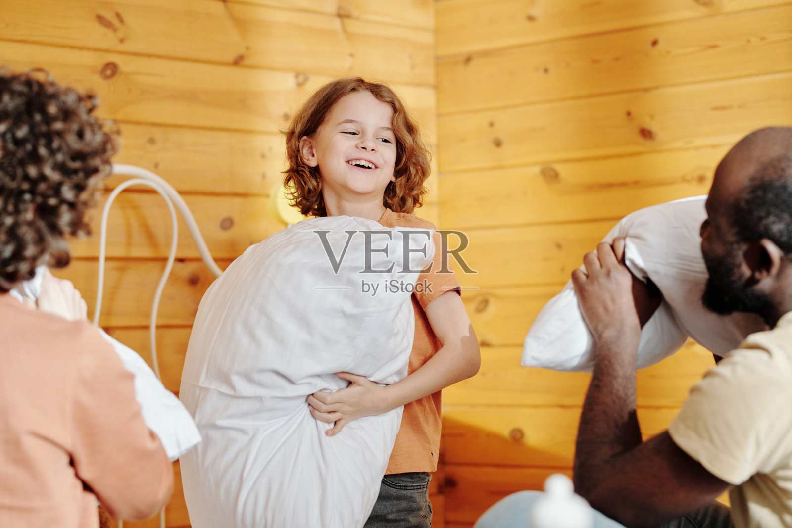 快乐的小男孩抱着枕头看着爸爸玩耍照片摄影图片