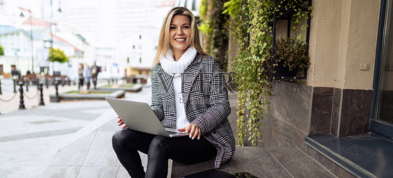 成年女性在办公室外的笔记本电脑上工作,坐在台阶上微笑着看着相机,商业风险保险概念照片摄影图片