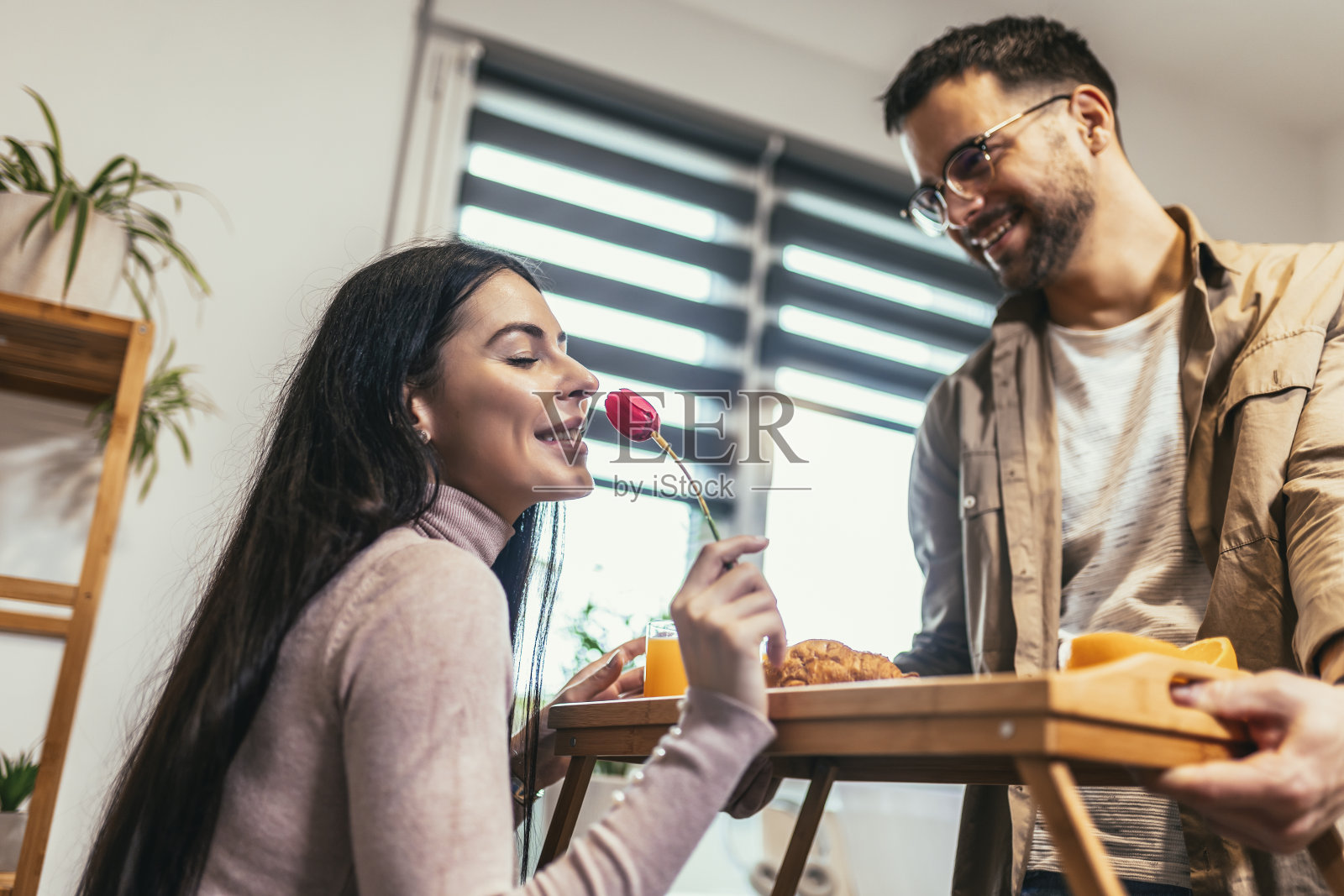 男人端着早餐托盘给一个快乐放松的女人照片摄影图片