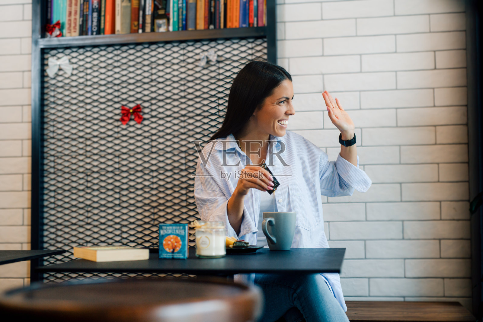 年轻女子喝咖啡,看着窗外坐在餐桌上的餐厅。照片摄影图片