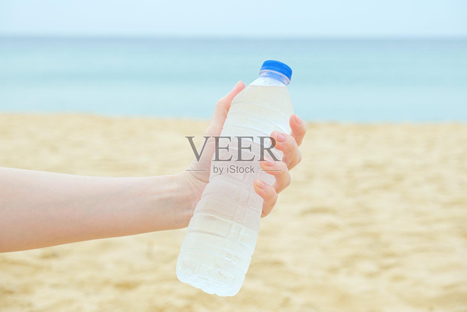 一名女子手里拿着一个塑料瓶,里面装着干净的饮用水照片摄影图片