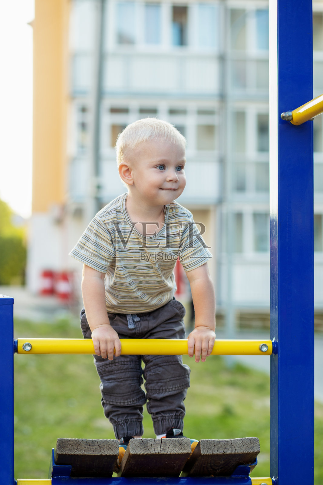 小男孩在操场上爬。可爱的微笑的孩子在户外玩耍。幼儿园的概念照片摄影图片