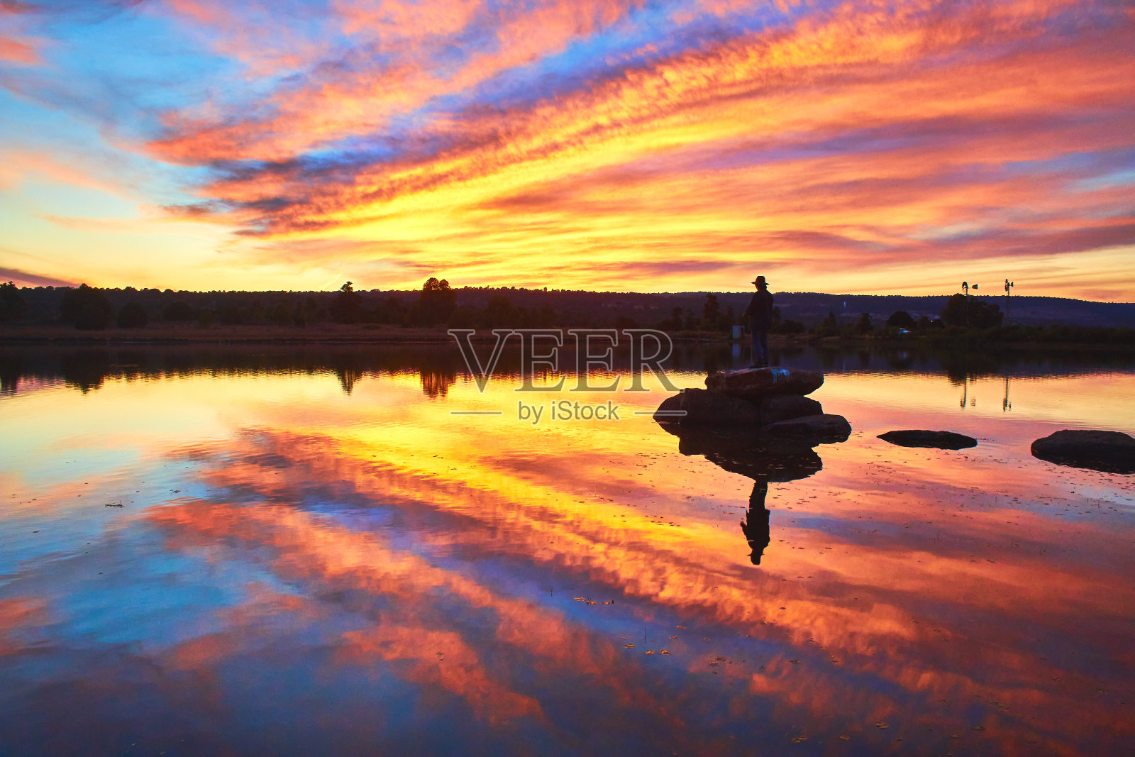 美丽的日落时分,在蒙特埃斯科韦多萨卡特卡斯Gamboa湖中岩石上的孤独的人照片摄影图片