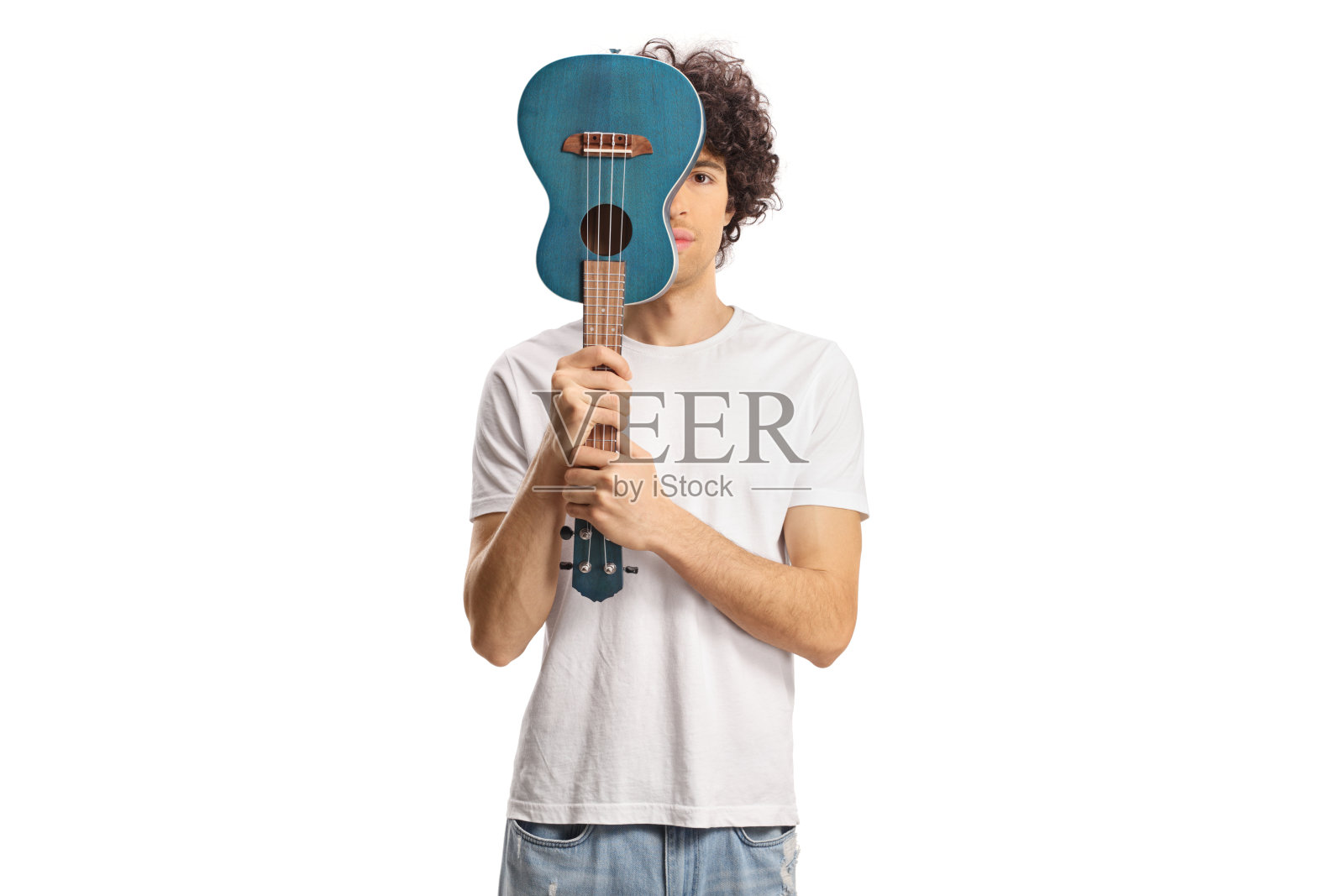 年轻的卷发男子拿着尤克里里在他面前照片摄影图片