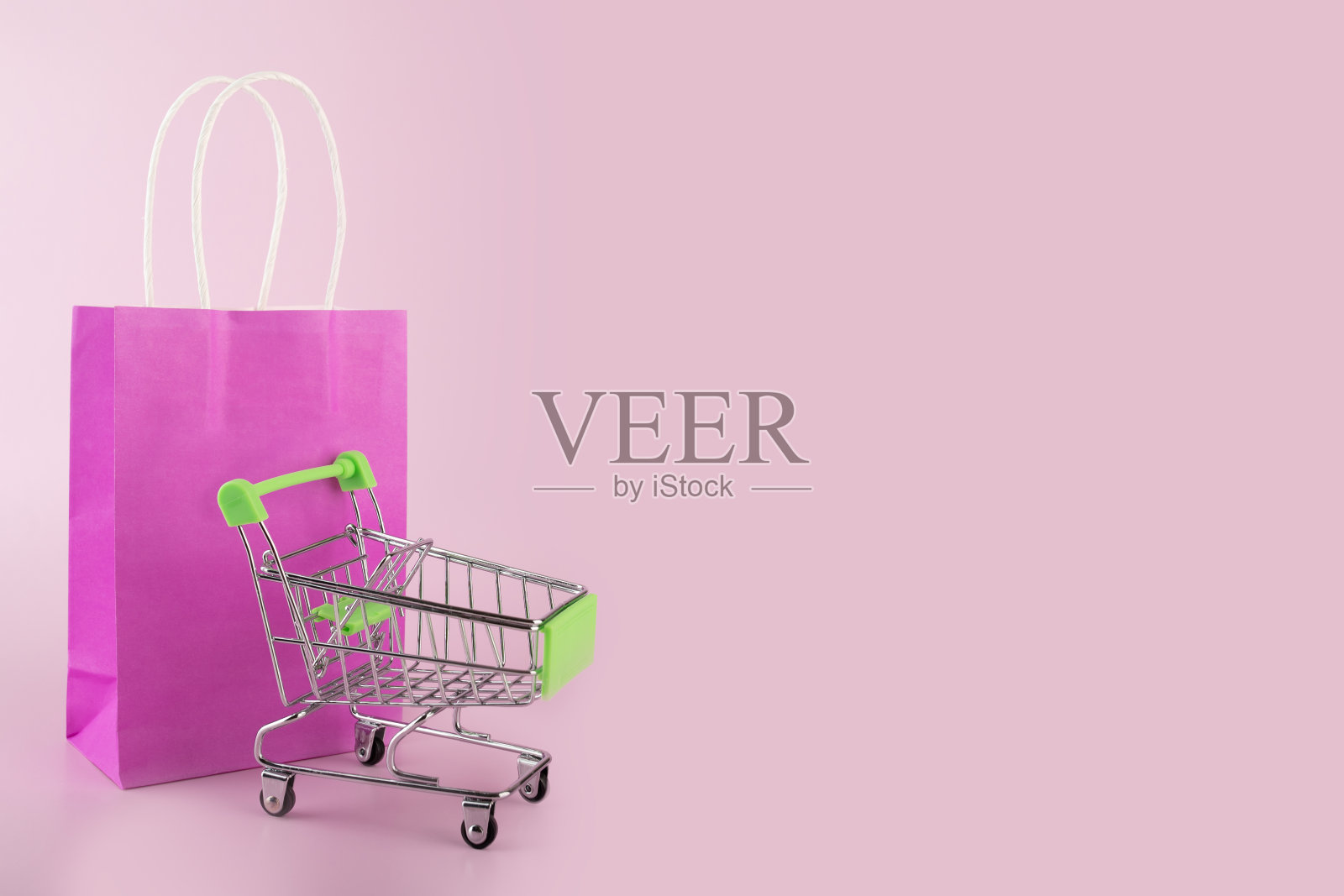 网上超市,购物袋与超市手推车在粉红色的背景,商店包装,礼品袋,销售和折扣照片摄影图片